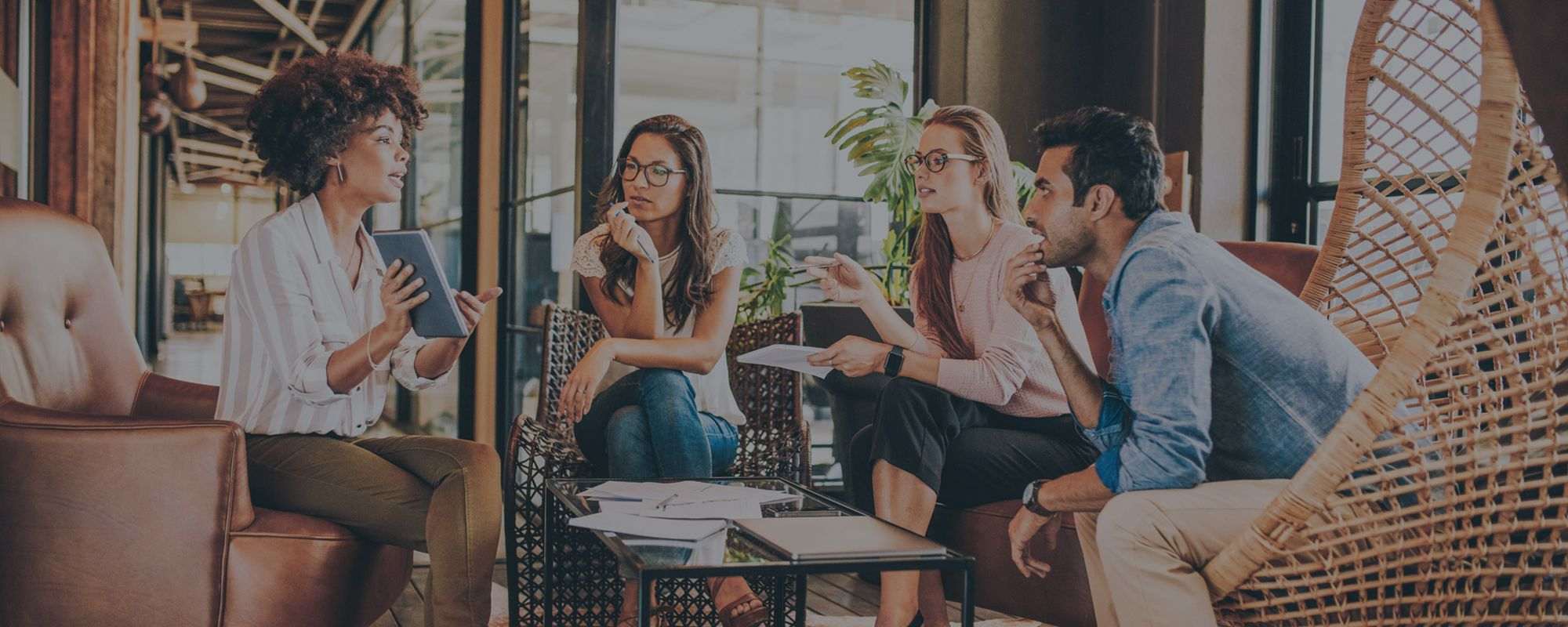 Four colleagues of different backgrounds discussing work around a coffee table