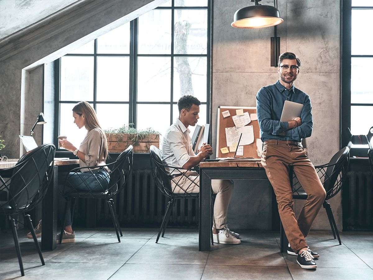 A KC Infotech consultant in a modern office, with colleagues working at desks behind him